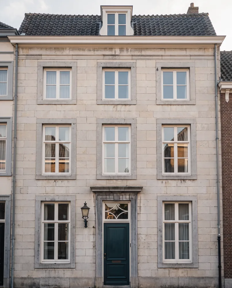 Frontaal beeld van een Maastrichts herenhuis van mergel met drie verdiepingen en een petrolgroene voordeur