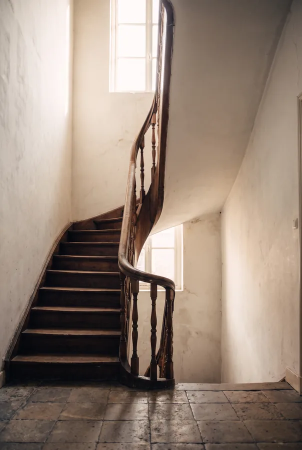 Een eikenhouten trappenhuis in een historisch pand, met daglicht van boven